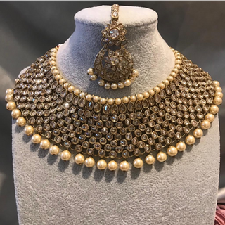 Luxury antique gold finish Kundan bridal necklace set featuring intricate detailing with matching jhumka earrings and maang tikka, elegant statement jewelry for South Asian weddings and nikah ceremonies, as seen in www.taniska.com