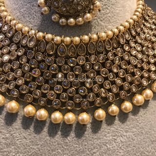 Luxury antique gold finish Kundan bridal necklace set featuring intricate detailing with matching jhumka earrings and maang tikka, elegant statement jewelry for South Asian weddings and nikah ceremonies, as seen in www.taniska.com