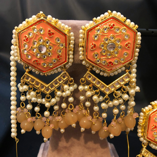 Luxury peach-orange meenakari Kundan choker necklace set with matching jhumka earrings and maang tikka, vibrant statement jewelry for South Asian bridal weddings and festive occasions.